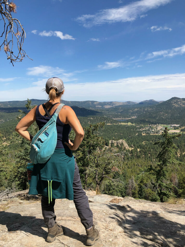 Kristina staring out to the trees and land below from a mountain.